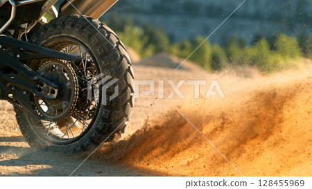 Flying rocks and dust from the wheel of a motocross bike at the start of the race 128455969