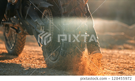 Flying rocks and dust from the wheel of a motocross bike at the start of the race 128455972