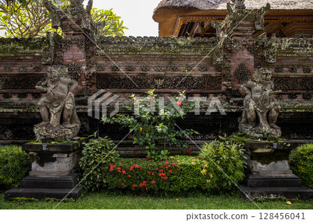 Monkey sculpture fully covered with green moss in Ubud's Monkey Forest. Bali, Indonesia. 128456041