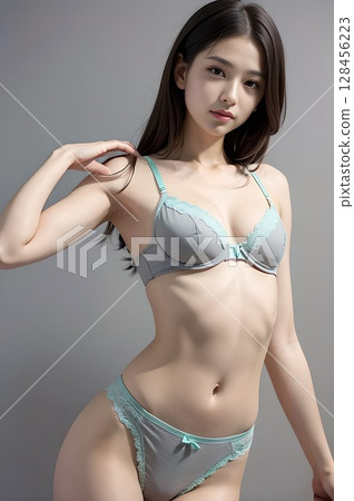 A woman in a grey-green bra and cotton panties with one hand on her shoulder 128456223