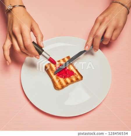 Female hands spreading red lipstick on toast using knife with curious attitude 128456534
