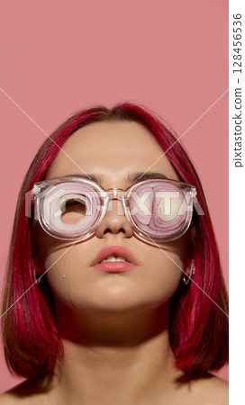 Woman wearing glasses with onion slices showing stoic calm and tearful reaction 128456536