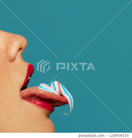 Red lips licking toothpaste from tongue with playful expression on turquoise background Red lips licking toothpaste from tongue with playful expression on turquoise background 128456555