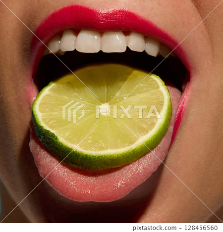 Open mouth with pink lips holding lime slice on tongue in pop art beauty image Open mouth with pink lips holding lime slice on tongue in pop art beauty image 128456560