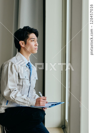 一個穿著工作服的年輕人在檢查某件東西 128457016