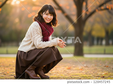 散發溫暖氣息的秋季時尚！在夕陽映照下的公園裡，一位戴著深紅色圍巾的女模特兒露出了燦爛的笑容。 128457245