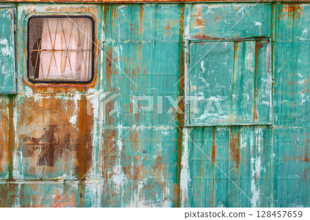 Rusty green metal wall with window and door in industrial setting 128457659