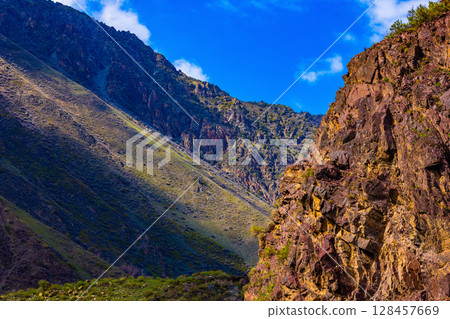 Rocky cliff in majestic mountain landscape at sunny summer day in Kyrgyzstan Rocky cliff in majestic mountain landscape at sunny summer day in Kyrgyzstan 128457669