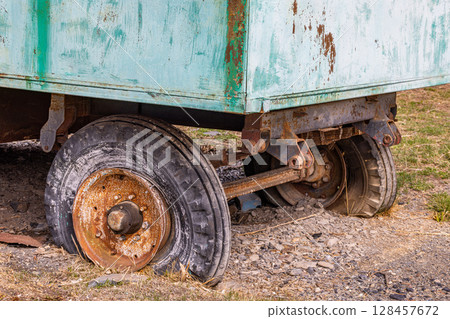 Rusty old trailer with partially visible wheels in rural setting 128457672