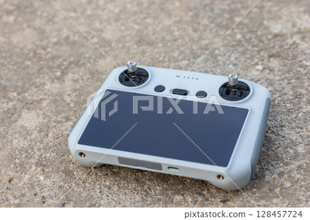 Drone remote control lying on concrete surface outdoors during daytime 128457724