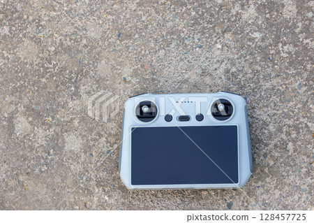 Remote control resting on concrete ground outdoors during daytime Remote control resting on concrete ground outdoors during daytime 128457725