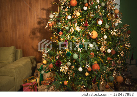 Merry Christmas Xmas happy holidays. Golden ornament decoration ball and defocused garland lights on classic decorated Christmas tree. Christmas tree with brown ornaments. Christmas eve at home Merry Christmas Xmas happy holidays. Golden ornament decoration ball and defocused garland lights on classic decorated Christmas tree. Christmas tree with brown ornaments. Christmas eve at home 128457998