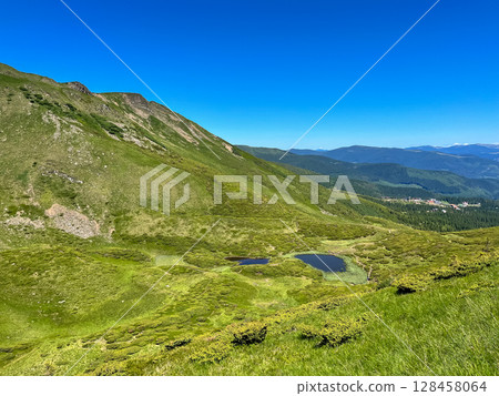 Mountain landscape with green hills and a blue sky. Mountain landscape with green hills and a blue sky. 128458064