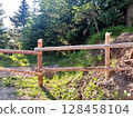 A rustic wooden fence in a lush forest setting. 128458104