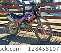 Adventure motorbike parked outdoors by a rustic fence 128458107