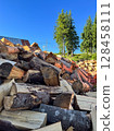 Large pile of chopped firewood under a clear blue sky. 128458111