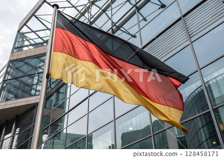 German flag waving in front of modern glass building. German flag waving in front of modern glass building. 128458171