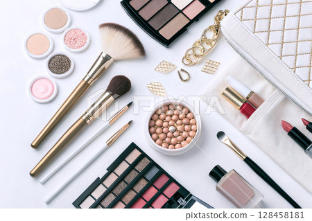 Flatlay of makeup products with brushes and accessories. 128458181