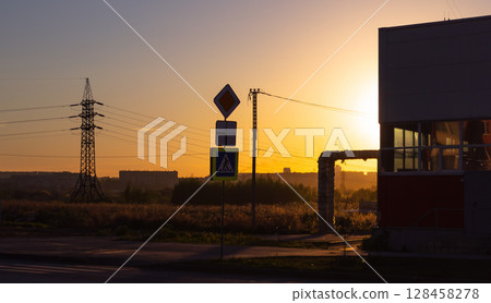 A road sign and other infrastructure in the light of the setting sun 128458278