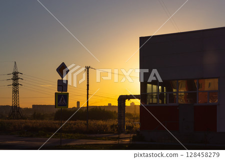 A road sign and other infrastructure in the light of the setting sun 128458279