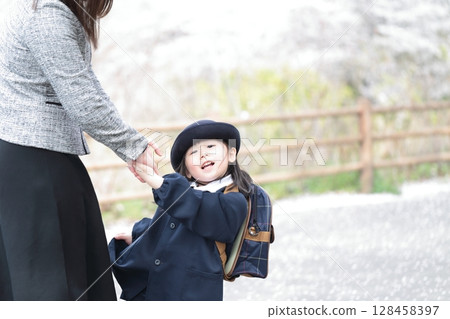 Cherry blossoms and a 3-year-old girl and her mother at the kindergarten entrance ceremony 128458397