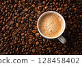 Coffee cup on roasted beans with visible foam. 128458402