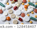 Various colorful pills scattered on a plain white background. 128458407