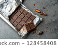 Partially unwrapped chocolate bar with almond. 128458408