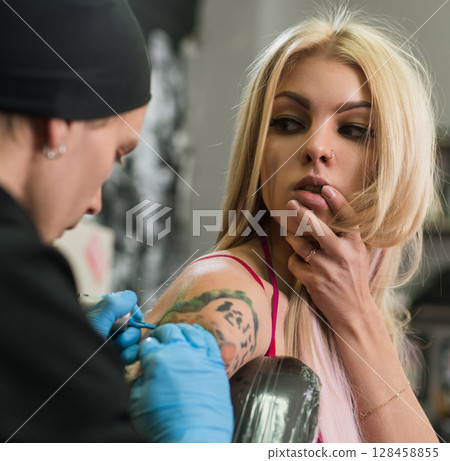 Sexy blonde and tattoo master at work in studio 128458855