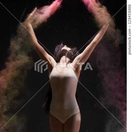 Gymnast streches body up in color dust cloud 128458866