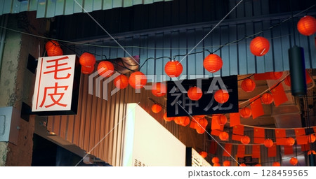 Red paper lanterns with chinese characters hang from a string, swaying gently in the breeze, illuminating the entrance to shen fang, creating a vibrant and festive atmosphere Red paper lanterns with chinese characters hang from a string, swaying gently in the breeze, illuminating the entrance to shen fang, creating a vibrant and festive atmosphere 128459565