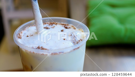 Skilled barista layering whipped cream and cocoa powder on chilled coffee, crafting gourmet summer beverage at modern cafe counter Skilled barista layering whipped cream and cocoa powder on chilled coffee, crafting gourmet summer beverage at modern cafe counter 128459644