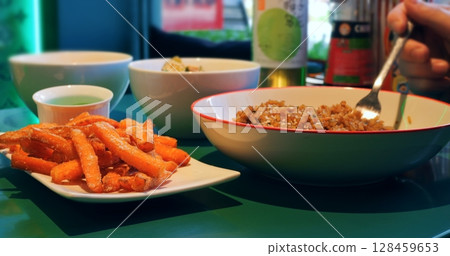 Vibrant culinary composition featuring rice mixed in bowl alongside crispy sweet potato fries, garnished with verdant green sauce, highlighting nutritious dining experience Vibrant culinary composition featuring rice mixed in bowl alongside crispy sweet potato fries, garnished with verdant green sauce, highlighting nutritious dining experience 128459653