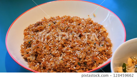 Seasoned fried rice and cucumber salad nestled in white bowls on vibrant turquoise table, showcasing colorful gourmet culinary composition Seasoned fried rice and cucumber salad nestled in white bowls on vibrant turquoise table, showcasing colorful gourmet culinary composition 128459662