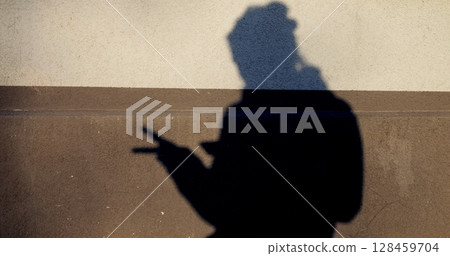 Silhouetted female shadow creating peace sign gesture on minimalist two tone wall, repeating symbolic hand movement with stylish, playful energy Silhouetted female shadow creating peace sign gesture on minimalist two tone wall, repeating symbolic hand movement with stylish, playful energy 128459704