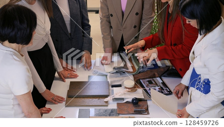 Group unites around table as designer guides fresh concepts, fueling designer insights that shape color palette, while designer synergy fosters dynamic interior solutions daily. 128459726