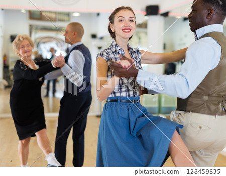 Woman with african man practising charleston dancing Woman with african man practising charleston dancing 128459835