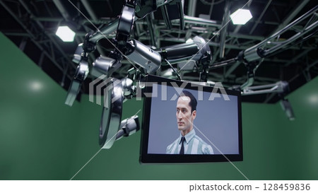 Advanced virtual production studio featuring robotic arms manipulating screen, dynamically changing background from grayscale to vibrant green screen, showcasing cutting edge filmmaking technology 128459836