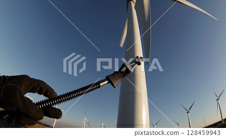 Maintenance worker uses a specialized wrench to tighten bolts securing a wind turbine rotor hub, ensuring smooth operation and energy generation 128459943