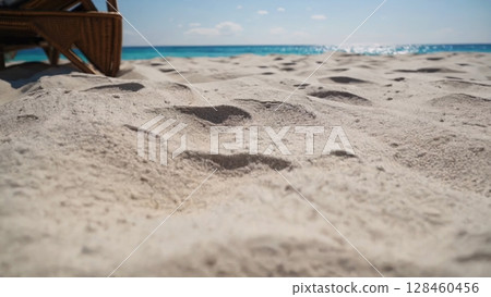 Luxurious wicker beach lounger nestling on pristine white sand, beckoning travelers with sweeping ocean panorama, embodying tropical tranquility and leisurely seaside relaxation Luxurious wicker beach lounger nestling on pristine white sand, beckoning travelers with sweeping ocean panorama, embodying tropical tranquility and leisurely seaside relaxation 128460456