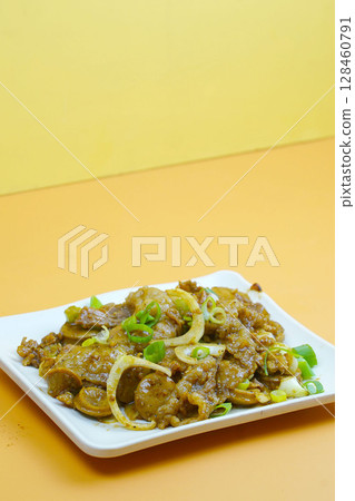 A savory stir-fried dish with sliced beef, mushrooms, onions, and green onions in a rich brown sauce, served on a white rectangular plate. 128460791