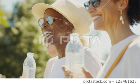 Three women enjoying walk in park with water, bright sunlight background Three women enjoying walk in park with water, bright sunlight background 128461625