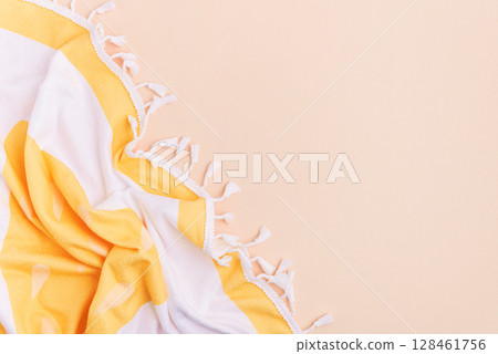 Yellow and white striped towel with fringe on a light background. Yellow and white striped towel with fringe on a light background. 128461756