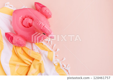 Beach essentials including an inflatable flamingo and towel on a light background. 128461757
