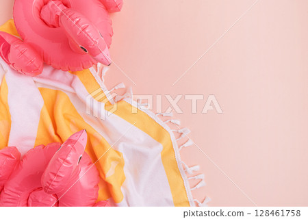 Beach essentials including an inflatable flamingos and towel on a light background. 128461758