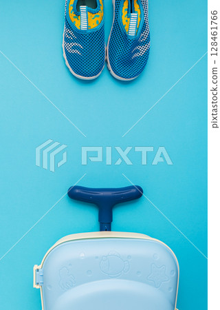 Water shoes and a child's suitcase on a blue background. 128461766