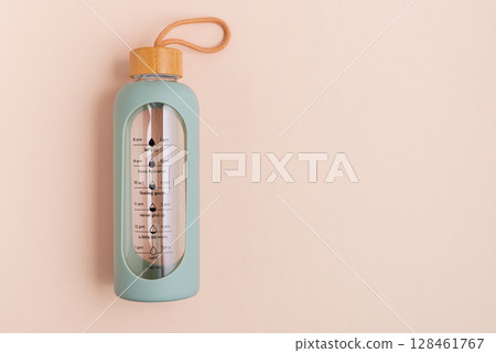 A glass water bottle with time markers on a light background. 128461767