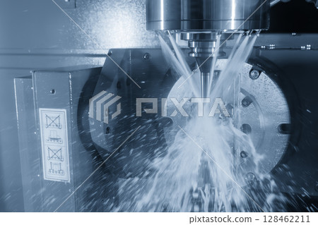 The 5-axis CNC milling machine cutting the automotive parts with liquid coolant method in the light blue scene. The 5-axis CNC milling machine cutting the automotive parts with liquid coolant method in the light blue scene. 128462211