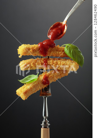 Fish fingers with basil and ketchup on a fork. 128462490