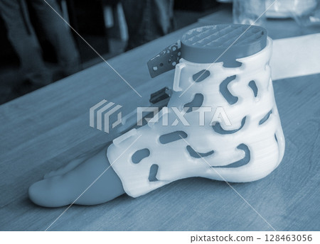 Prosthesis printed on a 3D printer from molten plastic on a plastic foot. Prototype of medical prosthesis for foot created on 3D printer. Medical orthosis, fixator, splint corset langet from plastic 128463056